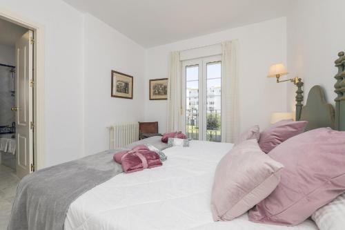 圣玛丽亚港Los Jandalos的卧室配有带粉红色枕头的大型白色床