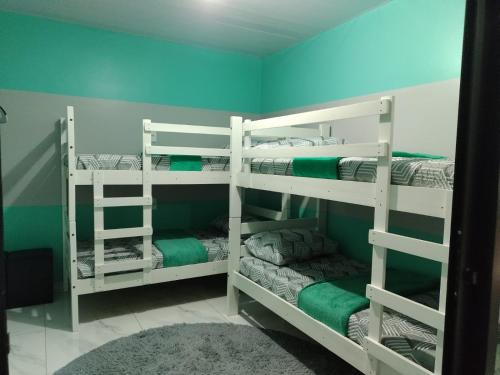 伊瓜苏Hostel Quintal de Casa的绿色墙壁的客房内设有两张白色双层床
