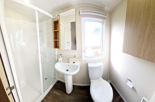 滨海克拉克顿Caravan With Decking And Free Wifi At Seawick Holiday Park Ref 27214sw的白色的浴室设有卫生间和水槽。