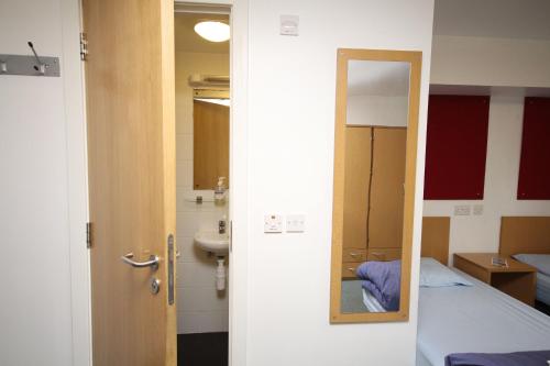 珀斯Perth Youth Hostel and Apartments的一间设有镜子、一张床和一个水槽的客房