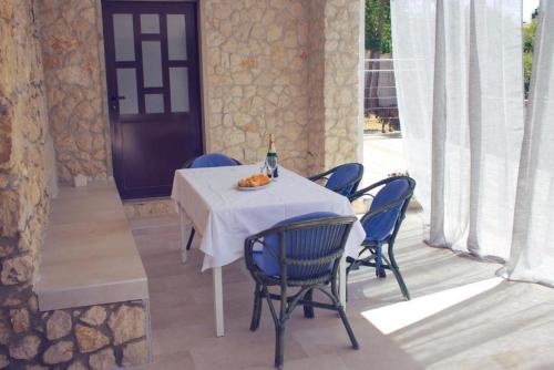 诺瓦利娅TEODORA - kamenný domek 300 m od moře的一张带蓝色椅子的桌子和一瓶葡萄酒