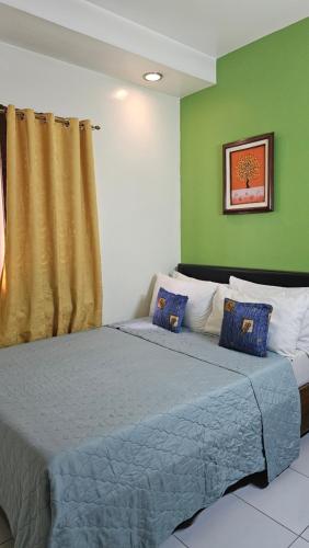 Marikina20 Studio Hotel的一间卧室配有一张带蓝色床单和绿色墙壁的床。
