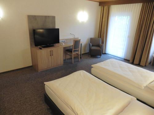 沃尔夫斯堡Hotels Landhaus Dieterichs的酒店客房设有两张床、一张桌子和一台电视。