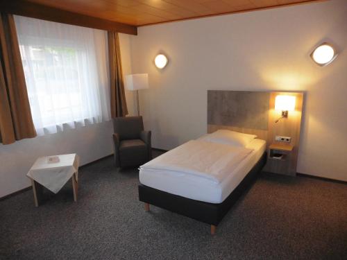 沃尔夫斯堡Hotels Landhaus Dieterichs的配有一张床和一把椅子的酒店客房
