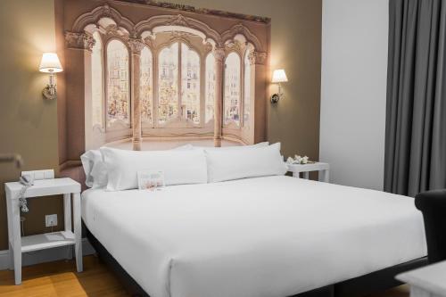 巴塞罗那卡斯蒂利亚阿提亚姆酒店的一间卧室配有一张大白色床和华丽的床头板