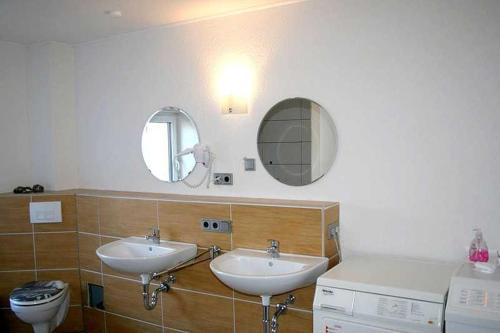萨斯尼茨萨斯尼茨公寓的一间带两个盥洗盆、卫生间和镜子的浴室