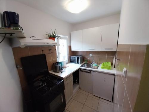 木洛希尼Apartmani Jadran的小厨房配有白色橱柜和黑炉