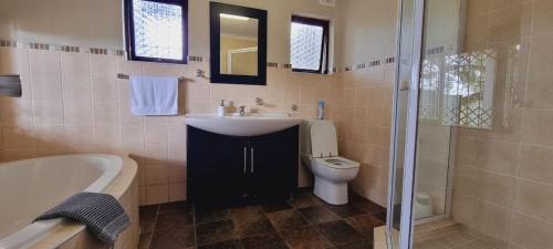 Bothaʼs HillSunset Manor的浴室配有盥洗盆、卫生间和浴缸。