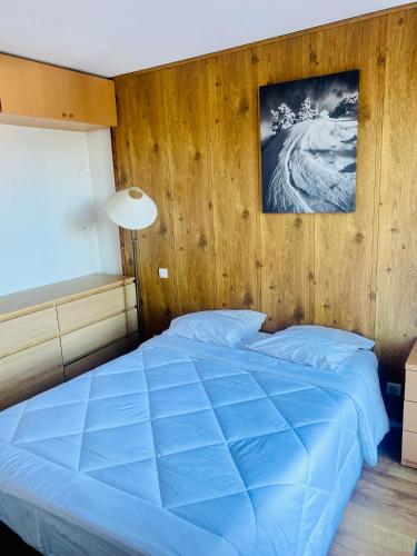 丰罗默奥代洛维亚Font-Romeu : T2 avec grande terrasse et garage的一间卧室配有一张蓝色的床和木墙