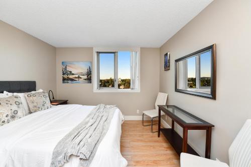 维多利亚Harbour Walk Executive Condo的一间卧室配有一张床、一张书桌和两个窗户。