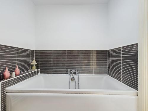 斯塔福德247 Serviced Accommodation in Stafford- 3BR Townhouse的浴室铺有黑色瓷砖,配有白色浴缸。