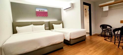 新山MILAN HOTEL的酒店客房设有两张床和一张桌子。