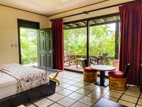 福尔图纳Arenal Manoa Resort & Hot Springs的一间卧室配有一张床,庭院配有桌椅