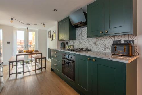 南安普敦Stylish Southampton City Centre House的铺有木地板的厨房配有绿色橱柜