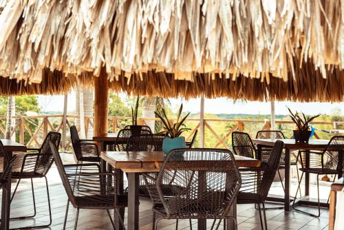 Xul-HaHotel y Beach Club Casa Mia Xulha -Bacalar的一间带桌椅和稻草伞的餐厅