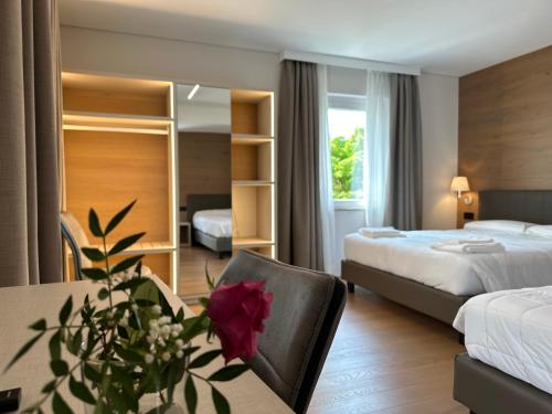 Magnano in RivieraHotel Riviera的酒店客房设有两张床和一张玫瑰花桌