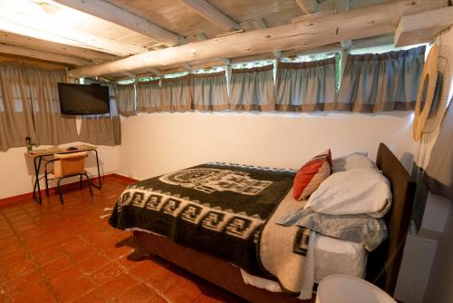 Los Baños del IncaCabaña Kinti Q'umir Umiña en Kinti Wasi的一间卧室配有一张床、一张书桌和一台电视