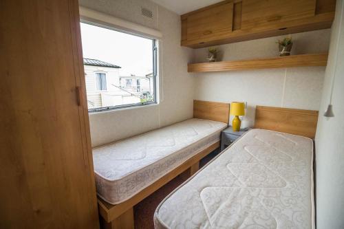 Great 4 Berth Caravan At Withernsea Sands Ref 79003hg的小房间设有两张床和窗户