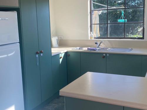 怀蒂昂格Bright Cosy Cottage的厨房配有蓝色橱柜、水槽和窗户。