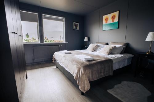 塞尔福斯Golden Circle Luxury Cottages的一间卧室设有一张大床和两个窗户。