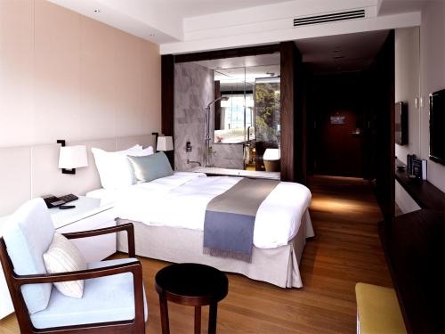 SaikaiOliveBay Hotel的卧室配有一张白色大床和一把椅子