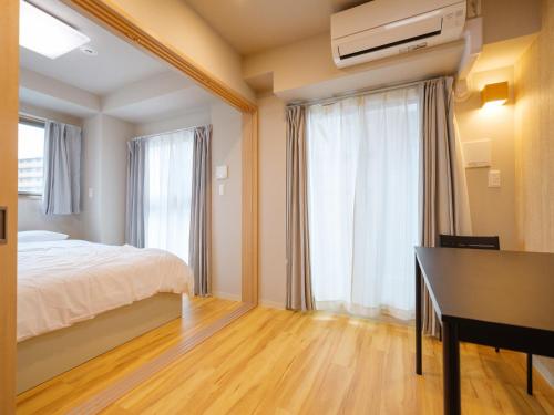 大阪DC桜の苑401洋式双人床的一间卧室配有一张床、一张书桌和一个窗户。