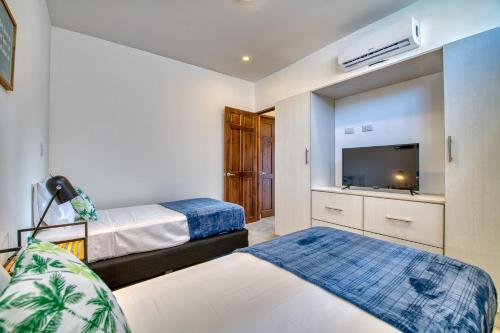 塔马林多Muna Tamarindo的一间卧室配有两张床和一台平面电视