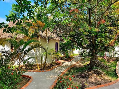 贡布Bohemiaz Resort and Spa Kampot的一条通往树木和鲜花的房子的小路