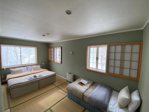 妙高Myoko Forest Lodge的一间卧室配有一张床、一张沙发和窗户。