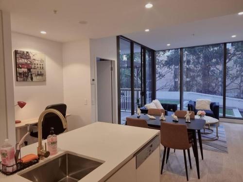 悉尼Sapphire Royale Suite in Macquarie Park的厨房以及带桌椅的起居室。