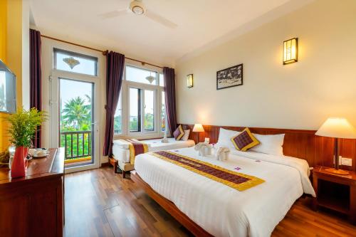 会安Hoi An Green Riverside Oasis Villa的酒店客房设有两张床和大窗户。