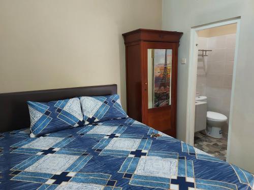 JomblangPenginapan Sriwijaya Semarang的一间卧室配有一张带蓝色棉被的床