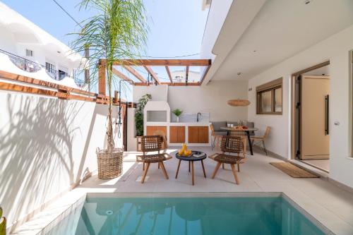 拉多斯Mariann Premium Suites的户外庭院设有游泳池和桌椅