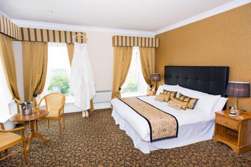 格伦贝赫Towers Hotel Glenbeigh的一间卧室配有一张大床和一张桌子及椅子