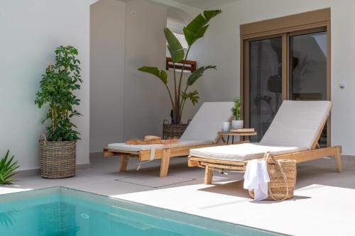 拉多斯Mariann Premium Suites的一个带两把躺椅的庭院和一个游泳池