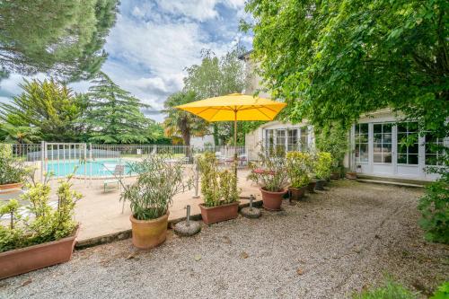 沙泰勒罗黎塞留别墅住宅酒店的一个带雨伞和盆栽植物的庭院和一个游泳池