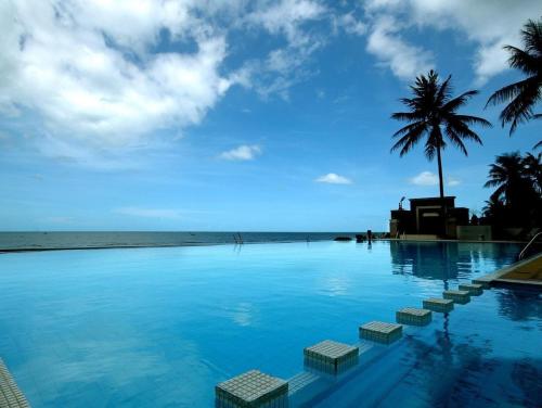 盼武里金松滩海滩度假酒店的一座棕榈树和海洋游泳池