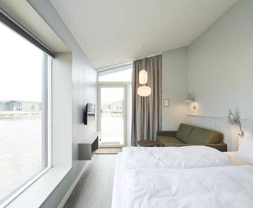勒兹比Hages Badehotel的一间卧室配有一张床、一张沙发和一个窗口