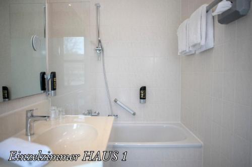 基姆湖畔普林Hotel Luitpold am See的一间带水槽和浴缸的浴室以及一部电话