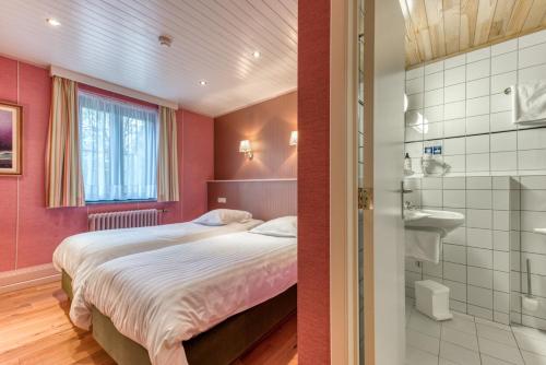 圣胡伯特Hôtel Le Cor de Chasse的一间卧室设有一张床和一间浴室。