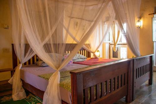 巴加莫约Firefly Boutique Lodge的一间卧室配有一张木床和天篷