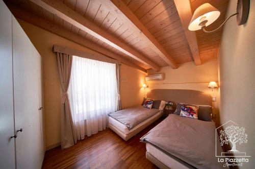西尔米奥奈Appartamenti La Piazzetta的客房设有两张床和大窗户。