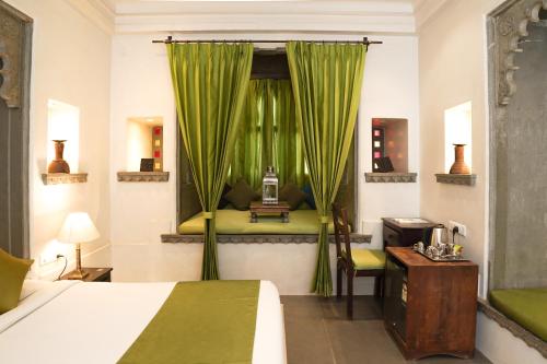 乌代浦马德里哈维里酒店的一间卧室设有床铺和一个带绿色窗帘的窗户。