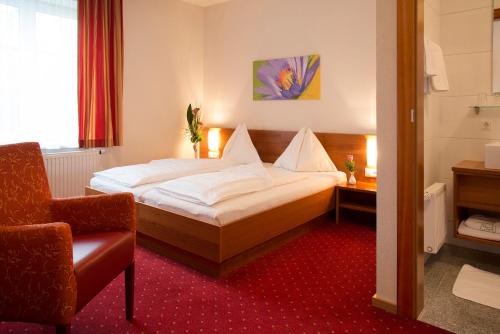 弗克拉布鲁克Schillerhof Hotel GARNI的配有一张床和一把椅子的酒店客房