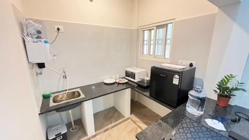 班加罗尔Goshen Inn的厨房配有带水槽的柜台和冰箱。