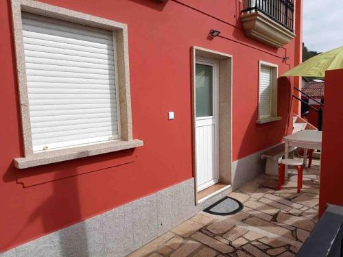 VilariñoAgradable casa con patio a 100 metros de la playa的红色的建筑,设有窗户和庭院