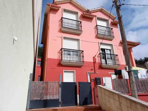 VilariñoAgradable casa con patio a 100 metros de la playa的粉红色的建筑,街道上设有黑色阳台