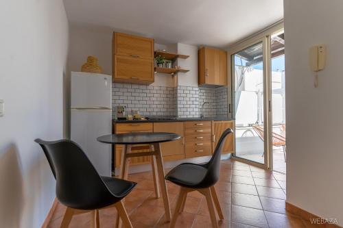 滨海波利尼亚诺Suite Novecento的厨房配有桌子、两把椅子和冰箱