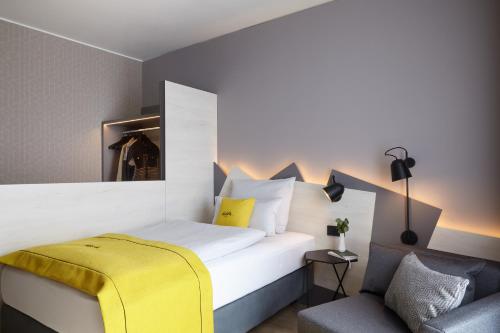 杜塞尔多夫acora Düsseldorf Airport Living the City的一间卧室配有一张带黄毯和椅子的床