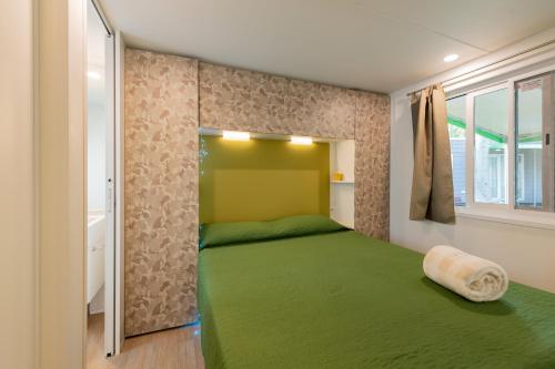 代森扎诺-德尔加达San Francesco Camping Village的一间卧室设有一张绿色的床和一个窗户。